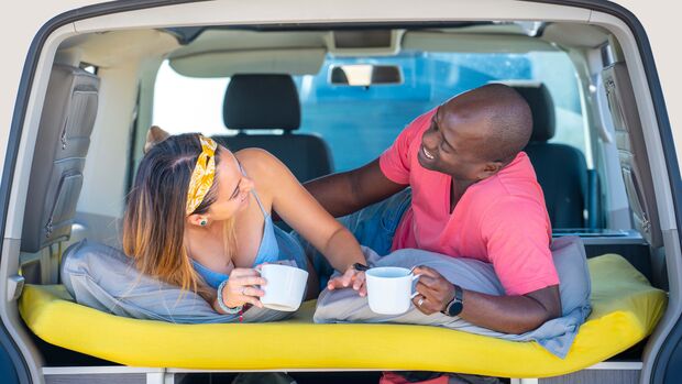 Couple young multi ethnic drinking coffee in camper van