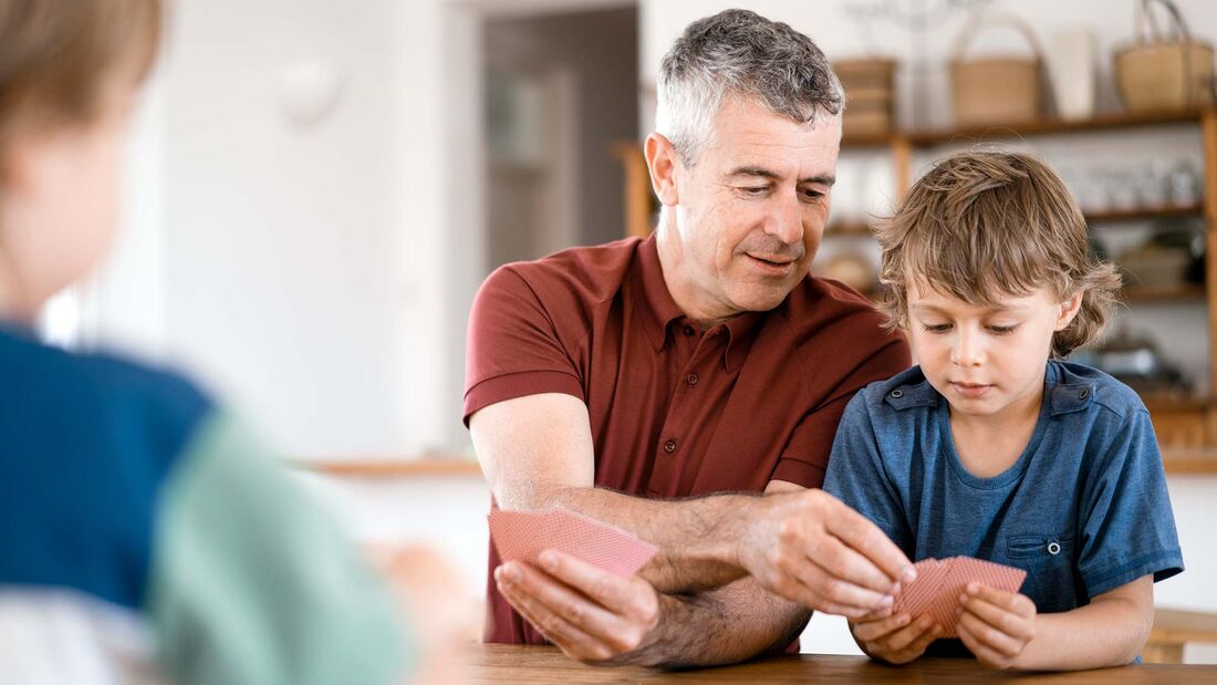 Father assisting son to play cards at home