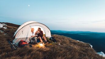 Senior couple camping in the mountains and eating a snack