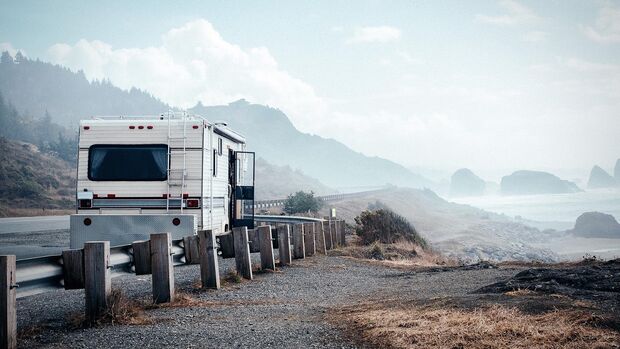 Travel Trailer Parked On Roadside By Mountain Against Sky